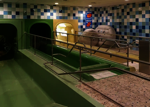Landing areas of closed tube slides with railings and tiled surroundings in the indoor area.