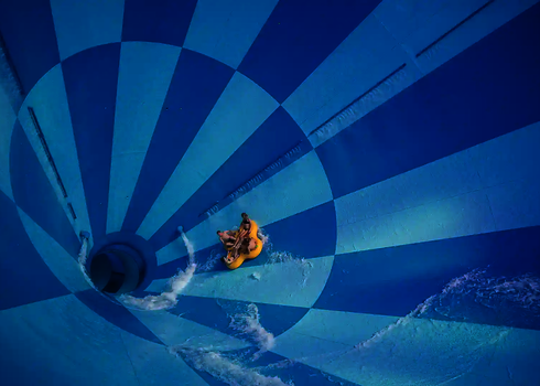 Blick von oben in den blauen Cyclone mit vier Personen im gelben Rutschreifen.