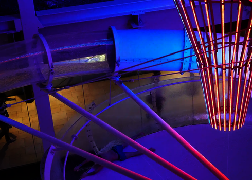 Rutschende Person wechselt aus Acryl-Element in eine beleuchtete Body Bowl Trichterrutsche.