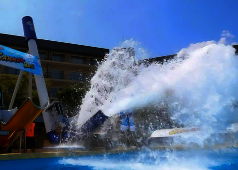 Ein blauer und ein orangefarbener Cannonball vor einem türkisfarbenen Schwimmbecken.