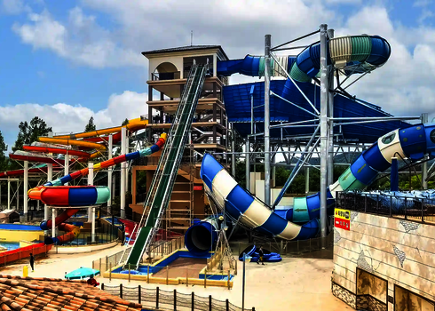 A colorful water park with several large tube slides and an integrated raft conveyor.