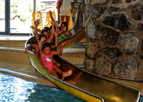 Mehrere Kinder rutschen fröhlich hintereinander eine gelbe WR560 Wasserrutsche hinunter.