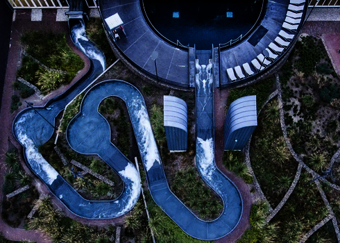 Vogelperspektive auf den kurvigen Wildwasserfluss auf dem Außengelände eines Wasserparks.