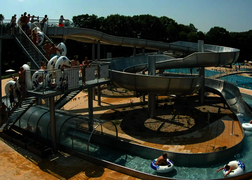Blick auf einen Wasserpark, in dem viele Badegäste für einen Rutshen-Komplex anstehen.