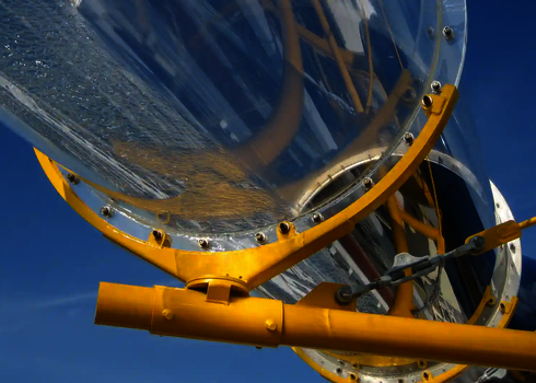 Transparentes Acryl-Element einer Wasserrutsche im Sonnenlicht mit gelber Stahlhalterung.