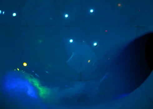 Innenansicht der Body Cone Wasserrutsche mit bunten Lichtern und Wassereffekten bei Nacht.