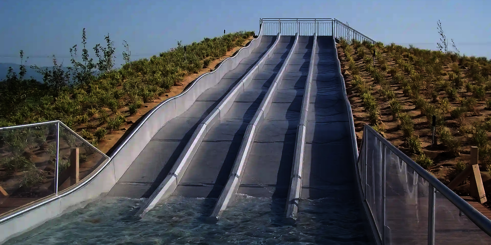Leere, mehrspurige Multilane im Freibad führt gerade ins Wasserbecken.