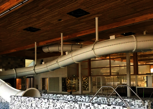 Innenansicht eines Hallenbades mit weißer RR900 Wasserrutsche.