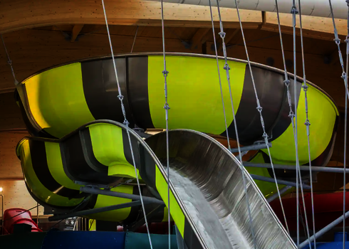 Nahaufnahme einer schwarz-gelben Wasserrutsche unter einem großen Holzdach.