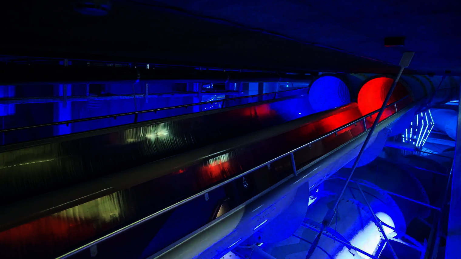 Raft Racer Reifenrutsche in nächtlicher Beleuchtung mit blau-rotem Tunnel.