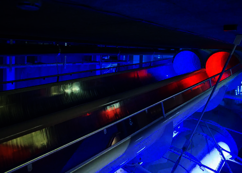 Raft Racer Reifenrutsche in nächtlicher Beleuchtung mit blau-rotem Tunnel.