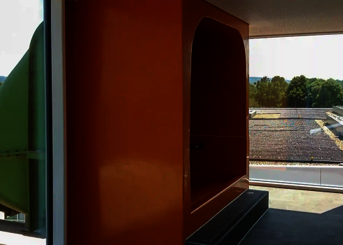 Einstiegskabine für Wasserrutsche im Innenraum, dahinter Fassadendurchdringung sichtbar.