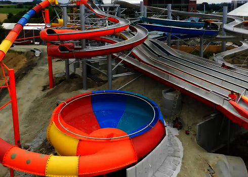 Seitenansicht auf einen Wasserpark, in dem sich eine bunte Body Bowl und ein Matracer befinden.