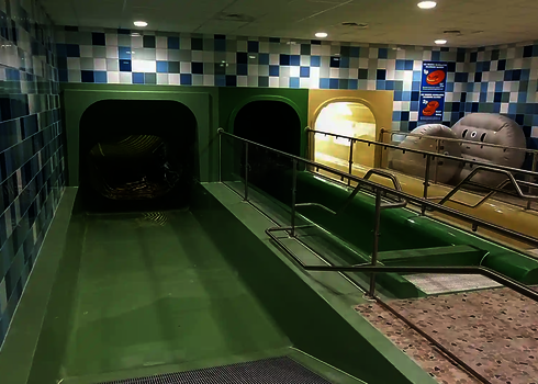 Indoor pool with three water slides and landing areas next to each other and rubber rings for use.