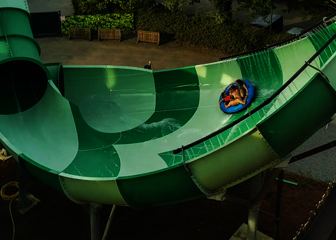 Vier Personen rutschen auf einem Rutschreifen durch die grüne Lotus Reifenrutsche.