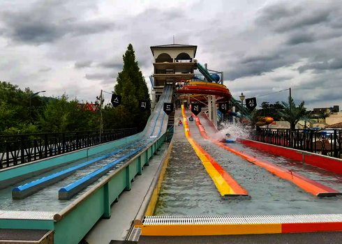 Mehrere bunte Bahnen einer Matracer Wasserrutsche im Outdoor Bereich.