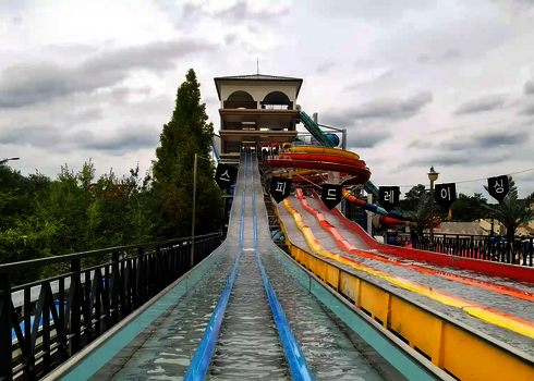 Bunte Rutschbahnen der Matracer Wasserrutsche, im Hintergrund Bäume.