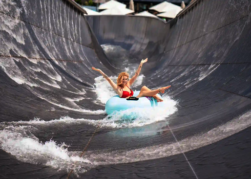 Lachende Frau im blauen Rutschreifen auf einer Edelstahl Wasserrutsche.
