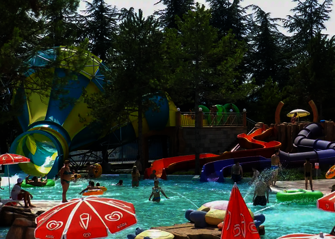 Ein Crazy Cone mit buntem Rutschensystem inmitten eines Wasserparks mit vielen Badegästen.