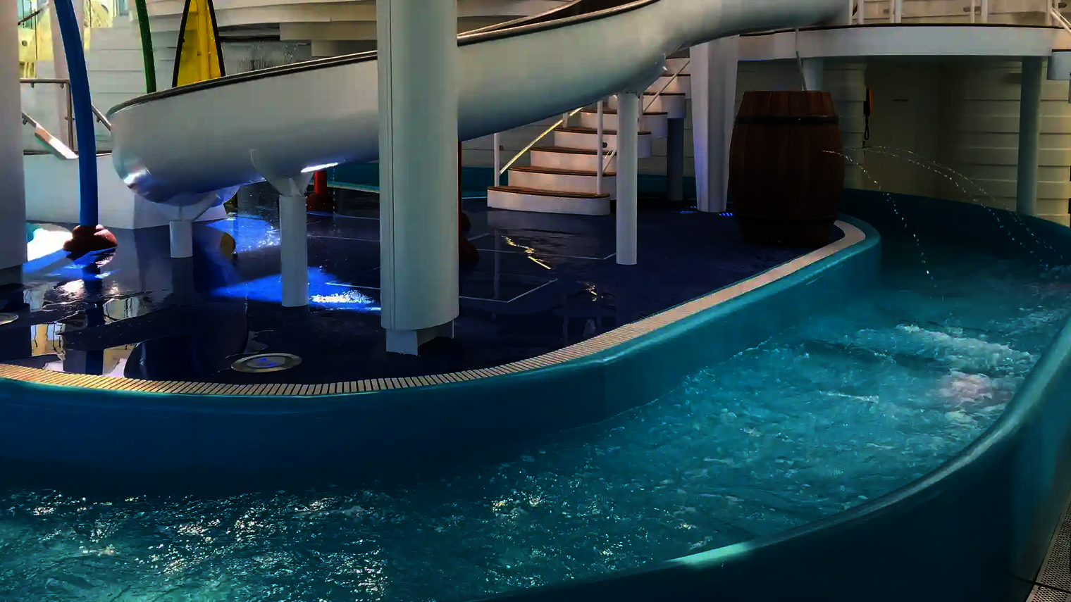 Wasser strömt durch den Lazy River vorbei an einer weißen Rutsche und Wasserspielen.