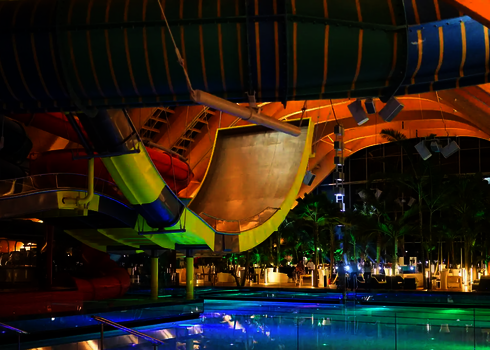 Indoor-Boomerang-Rutsche mit gelber Unterkonstruktion über einem großen Schwimmbecken.