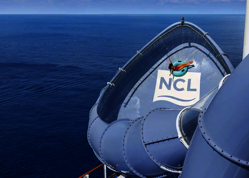 Person auf blauem Rutschreifen rutscht in der Lotus Wasserrutsche auf dem Meer.