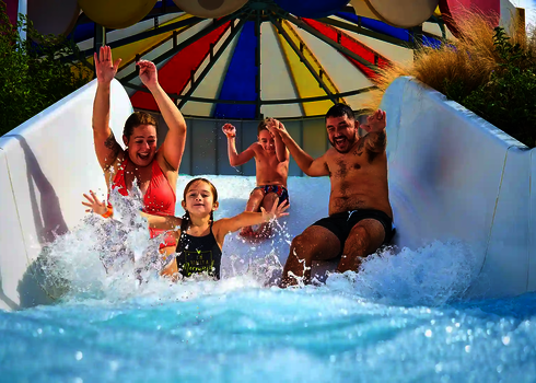 Eine Familie rutscht gemeinsam lachend durch den Wildwasserfluss.