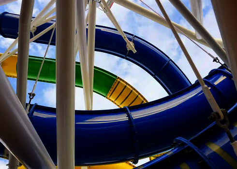 Mehrere Wasserrutschen vom Typ RR900 winden sich zwischen weißen Stahlträgern in den Himmel.