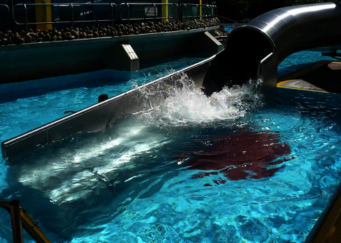 Tube slide ends with a powerful splash into an outdoor pool.