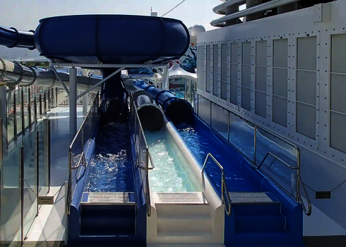 Two adjacent slide exits on a cruise ship with a water pool.