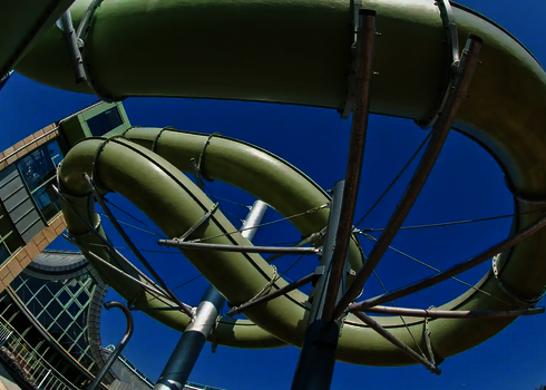 Eine grüne GFK Wasserrutsche die in ein Schwimmbad führt.