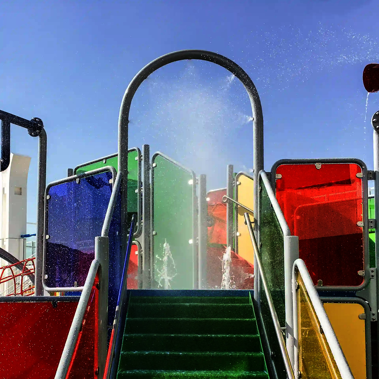 Wie-Spray Bauteil "Wasserbogen" auf bunter Wasserspielstruktur.