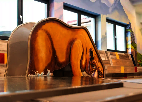  Eine Kleinkinderrutsche in Bärenform steht am Rand eines flachen Kinderbeckens.