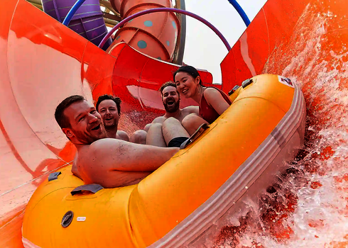 Vier Personen rutschen lachend in einem Reifen die RR2700, Wasser spritzt.