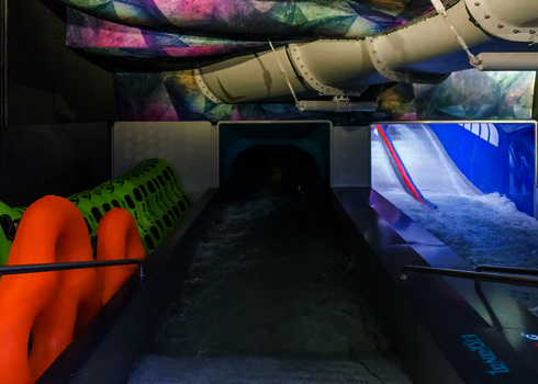 Dark exit area with green and orange double tyres under a colourful ceiling.