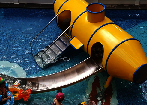 Kinder und Erwachsene befinden sich in einem Kinderbecken mit dem gelben Wie-Spray Element "U-Boot".