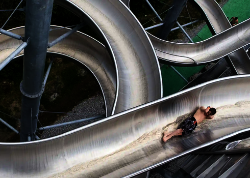 Ein Junge rutscht auf der WR1040 durch eine hochgelegene Edelstahlspirale.