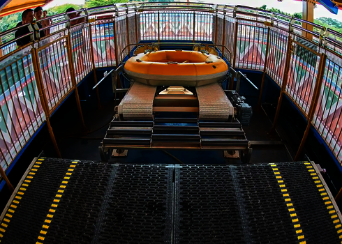 Close-up of a yellow slide raft on the side-guided conveyor belt of the raft conveyor.