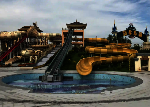 Front view of a water park with raft conveyor, several slides, and empty pool.