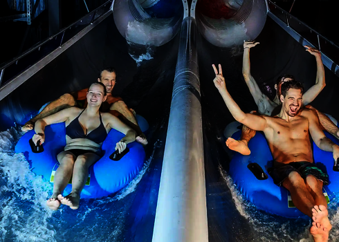 Zwei Doppelreifen mit Badegästen am Ausgang der Raft Racer Reifenrutsche.