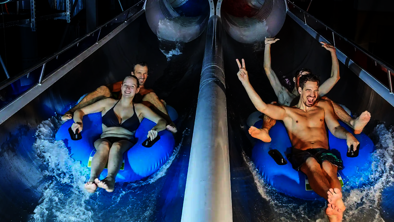 Zwei Doppelreifen mit Badegästen am Ausgang der Raft Racer Reifenrutsche.