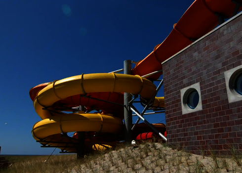 Eine gelbe RR1200 Wasserrutsche und ein orangefarbener Family Twister unter freien blauen Himmel.