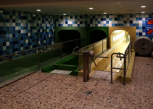 Sliding start with green and yellow channel, handrails and tiled floor.