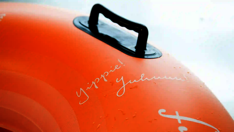 Nahaufnahme eines orangefarbenen Rutschreifens mit Griff und Schriftzug „Yippie! Juhuuu!“.