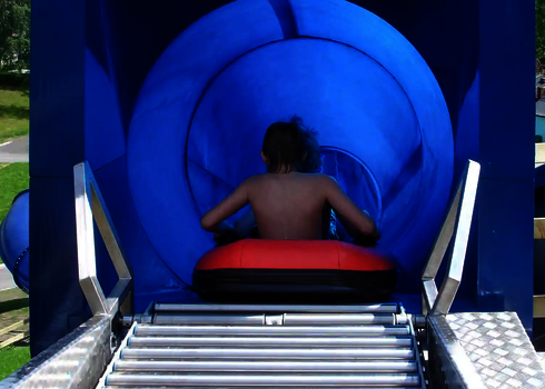 Kind sitzt im Reifen im blauen Startbereich der Harakiri Freizeitparkrutsche. 