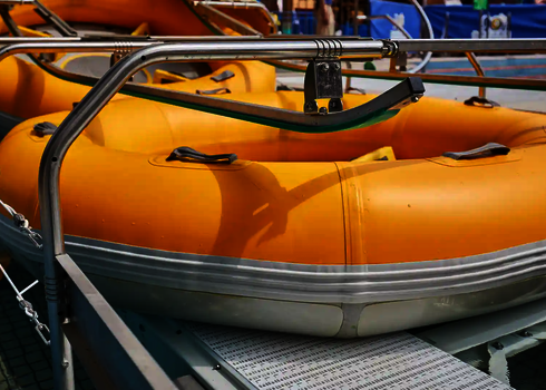 Yellow slide raft lies on the entry conveyor belt of the raft conveyor between guide rails.