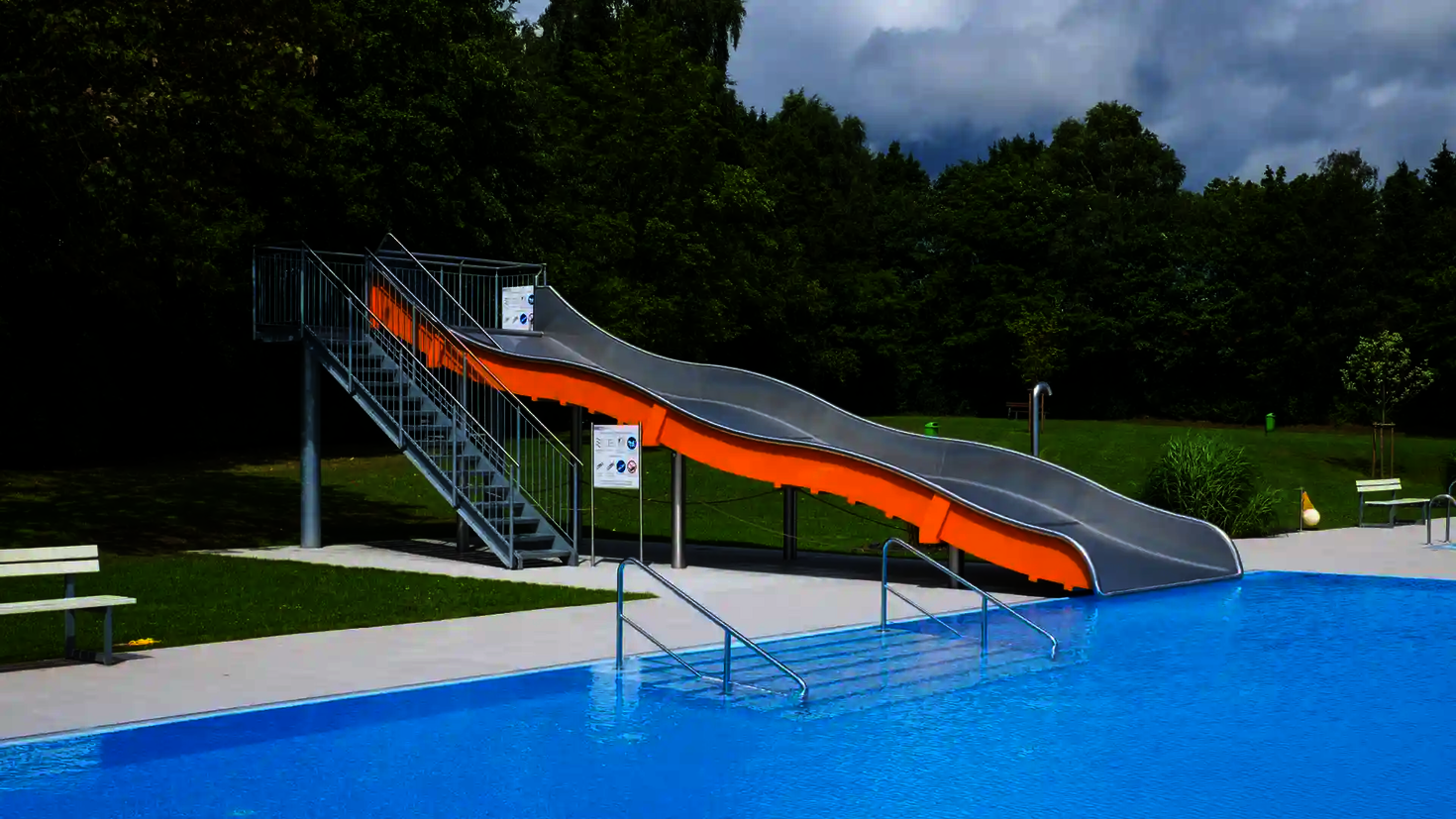 Eine Breitwellenrutsche mit orangefarbenen Seitenwänden in einem Freibad.