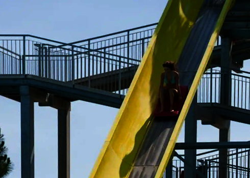 Frau rutscht auf einem Boot die steile Bahn der Aqua Shuttle Wasserrutsche hinunter.