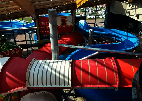 Innenbereich mit roten, weißen und blauen Wasserrutschen, Blick von oben auf die Anlage.