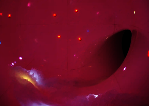 Wellenbewegung in pink beleuchtetem Rutschenraum mit Lichteffekten an der Wand.